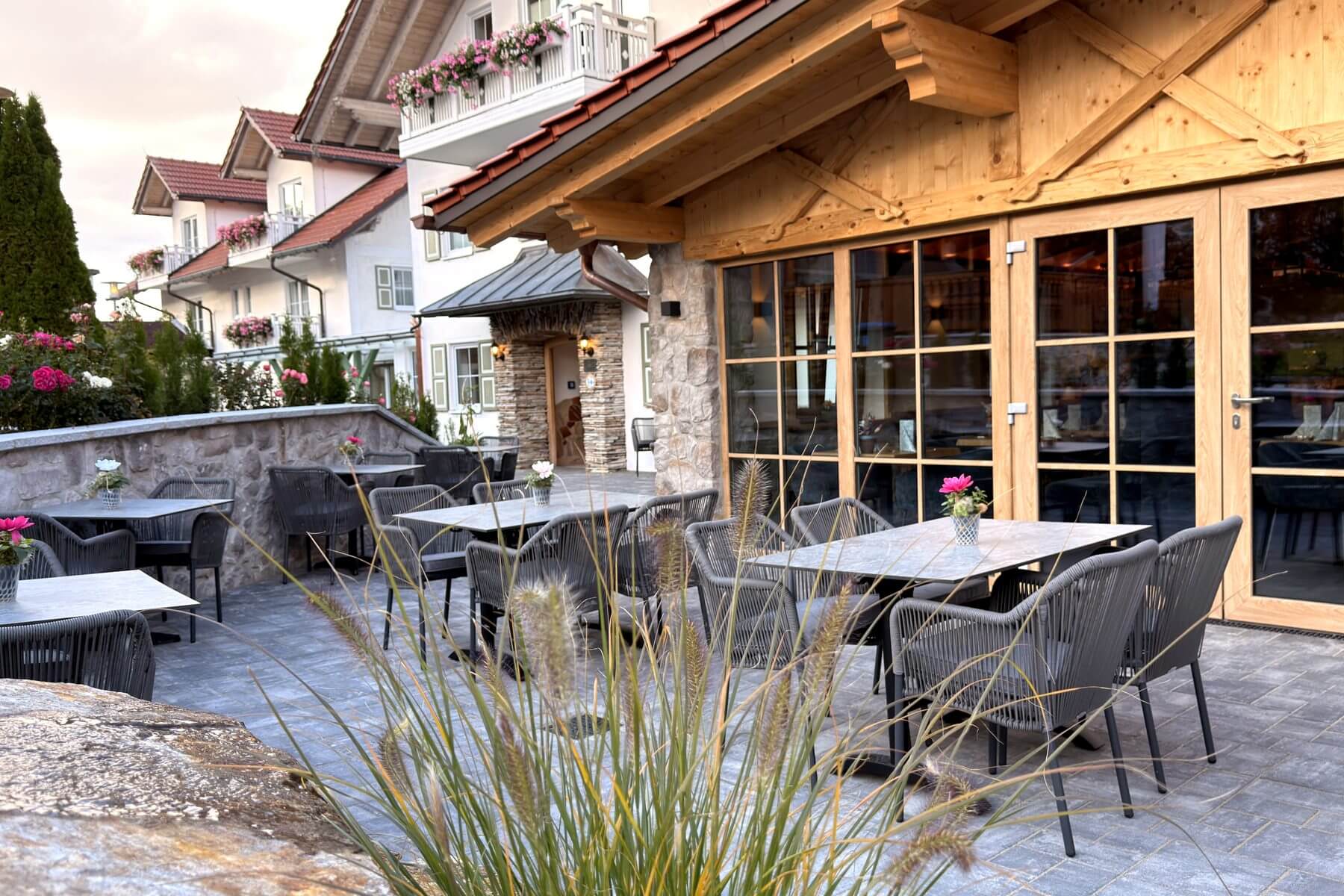 Terrassenbereich des Restaurant Pfeiffer am Wörthsee mit grauen Stühlen, Tischen und Blick zum Gebäude