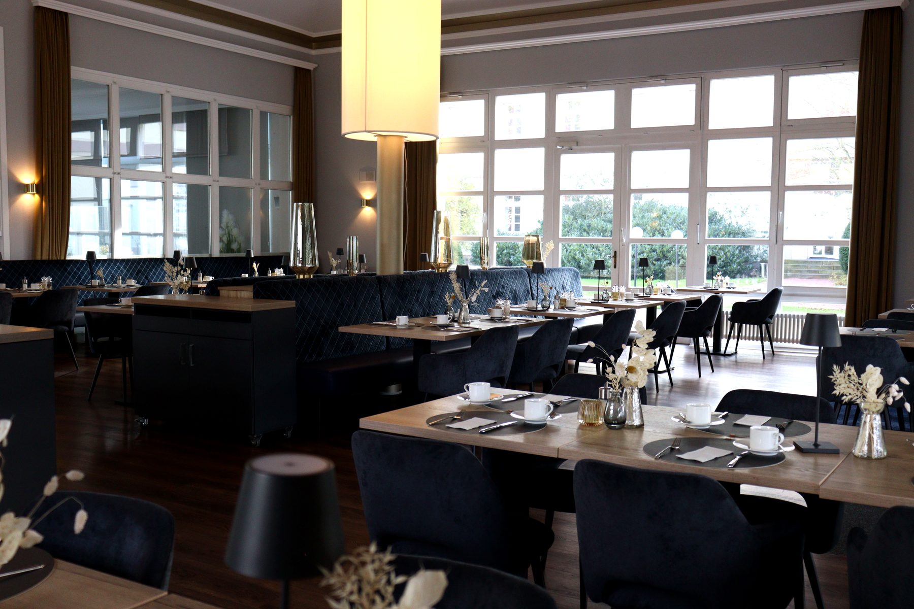 Restaurant im Hotel Stadt Hameln mit dunklen Tischen, Stühlen und hoher Fensterfront