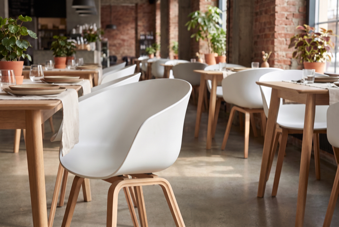 Weiße Schalenstühle an hellen Restauranttischen