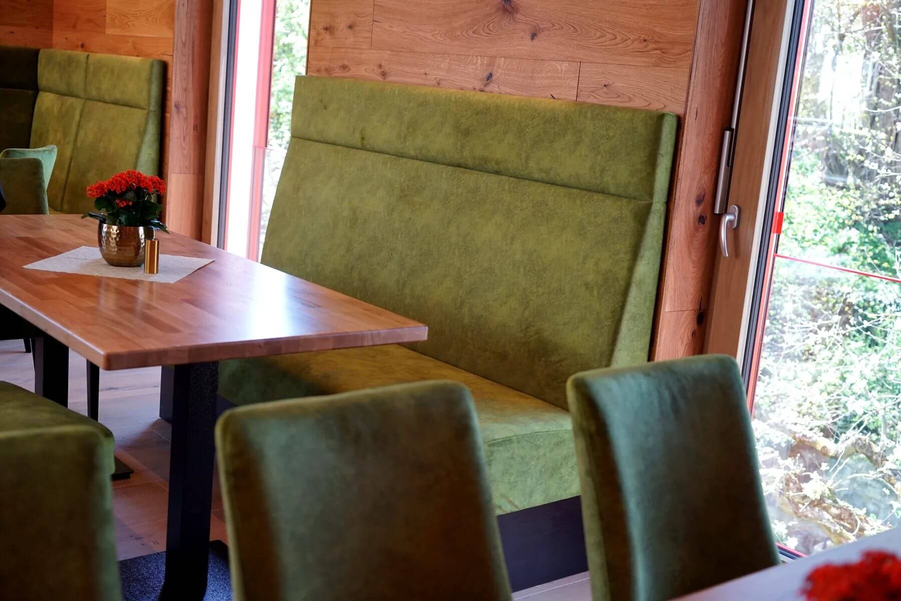 Detailansicht einer grünen Polsterbank Q 101 S mit Holztisch im Dorfladen Café Marktgraitz