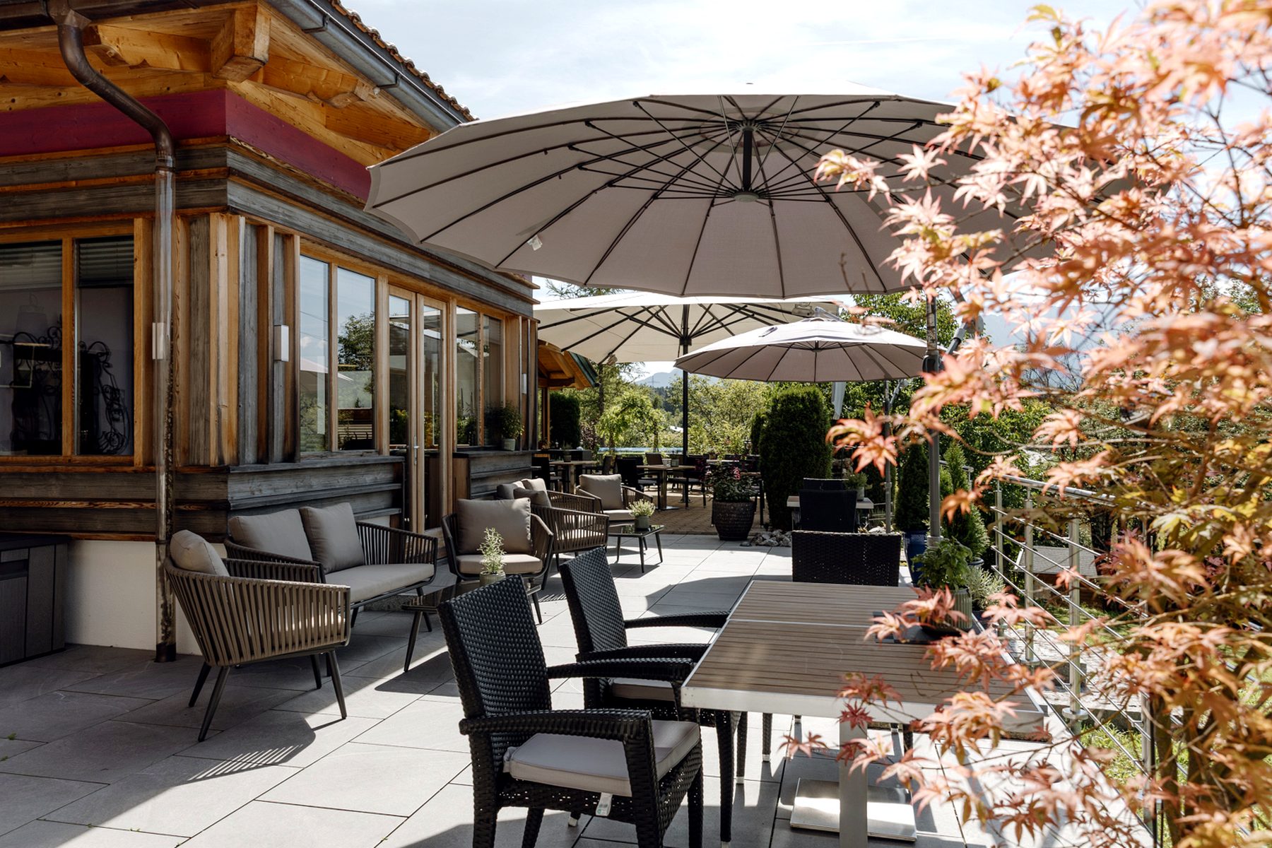 Terrassenbereich im Landhotel zum Bad in Krün mit Raminota Lounge Set, Sonnenschirm und Tischen