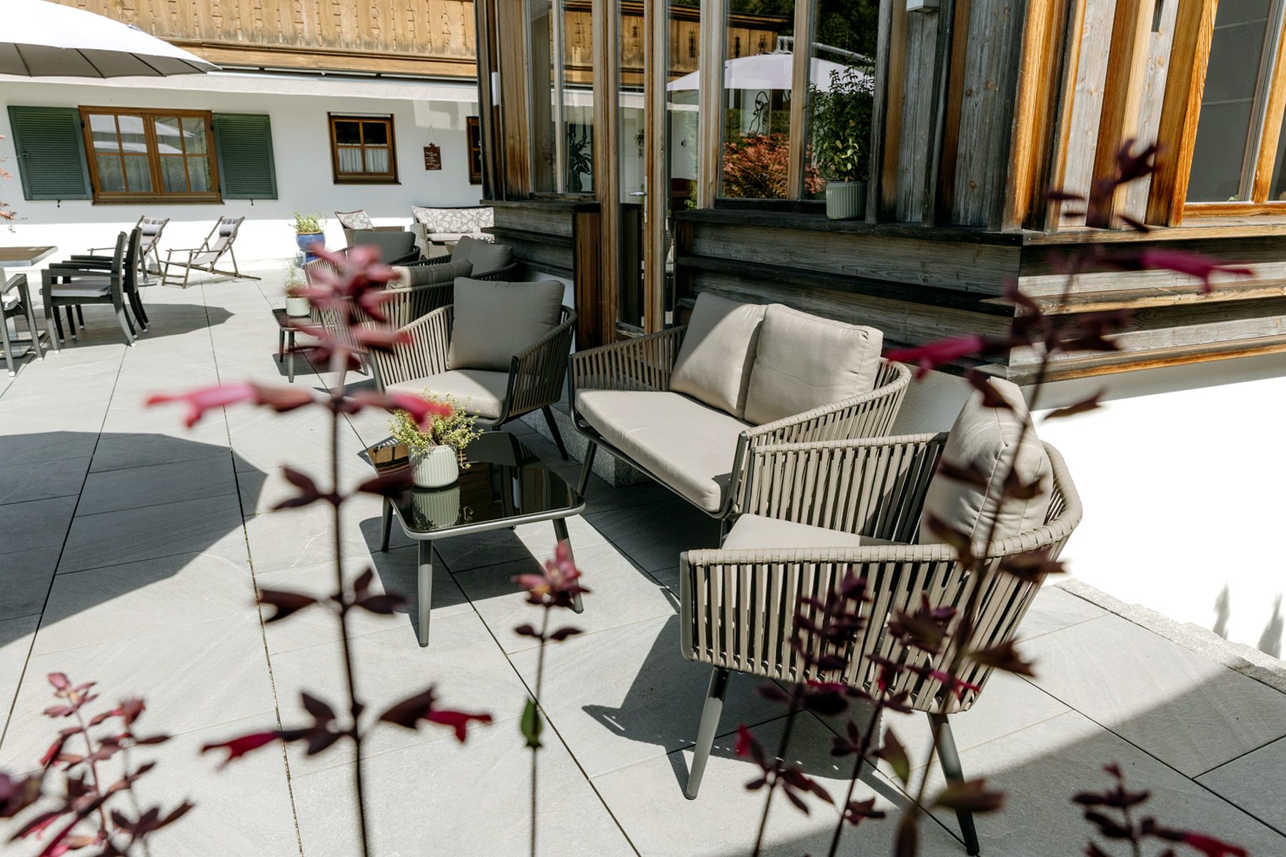 Loungegruppe auf der Terrasse des Esszimmer am Bichl mit Outdoor-Sesseln, Tisch und Sitzbank