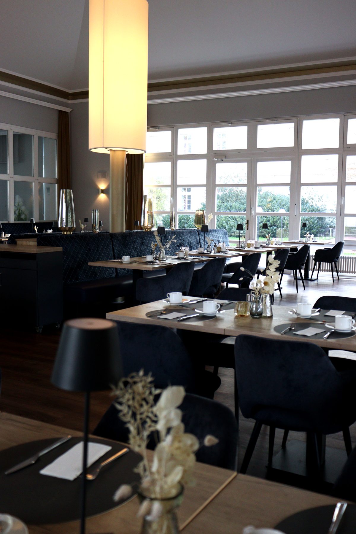 Hochformat des Restaurants im Hotel Stadt Hameln mit gedeckten Tischen und warmem Raumkonzept