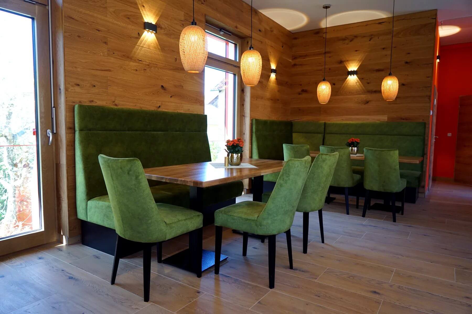 Gastraum im Dorfladen Café Marktgraitz mit Polsterbank, Holztischen und grünen Gastronomiestühlen