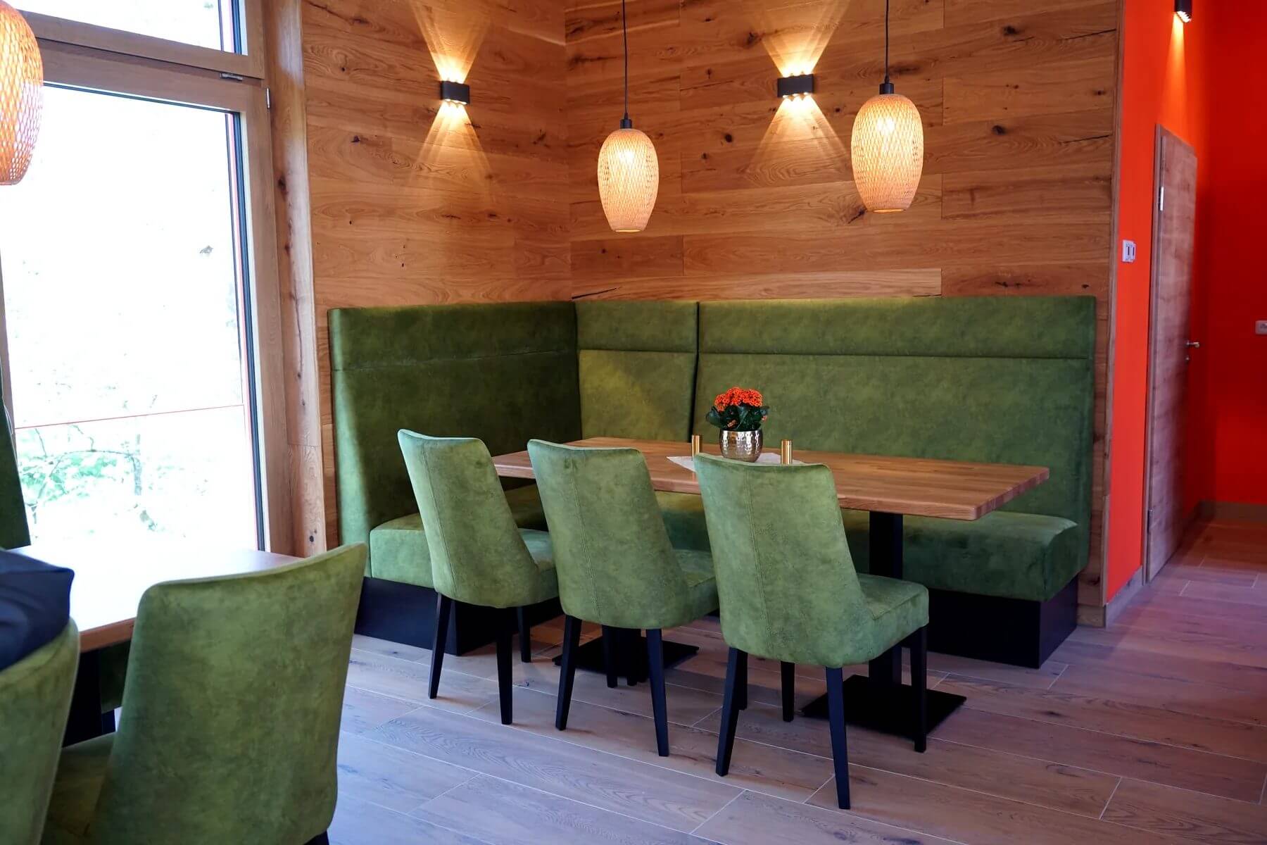 Gastraum im Dorfladen Café Marktgraitz mit grünen Polsterstühlen und Polsterbank an Holzwand