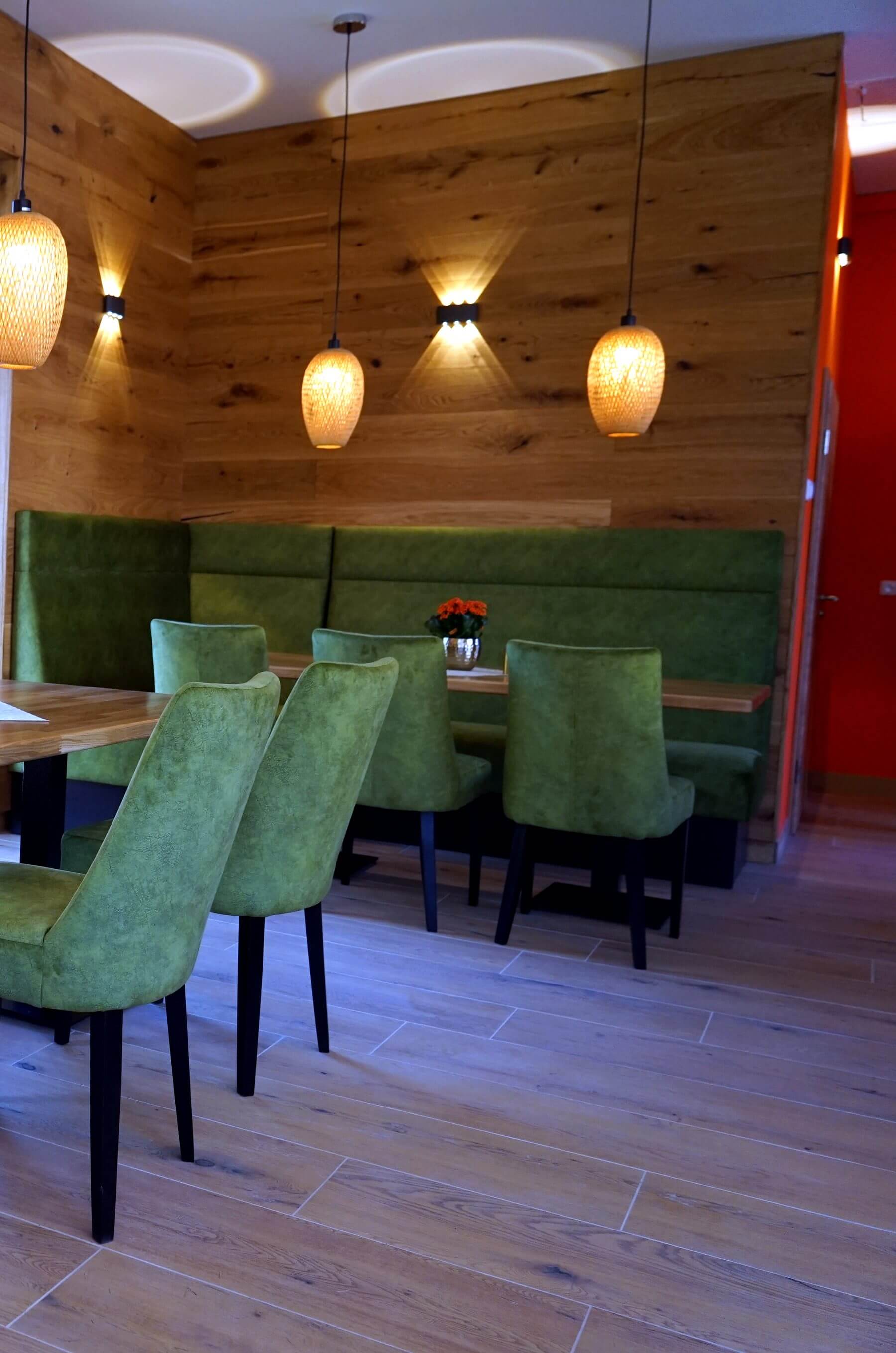 Sitzgruppe im Dorfladen Café Marktgraitz mit Holzwand, Pendelleuchten, Polsterbank und Gastronomiestühlen