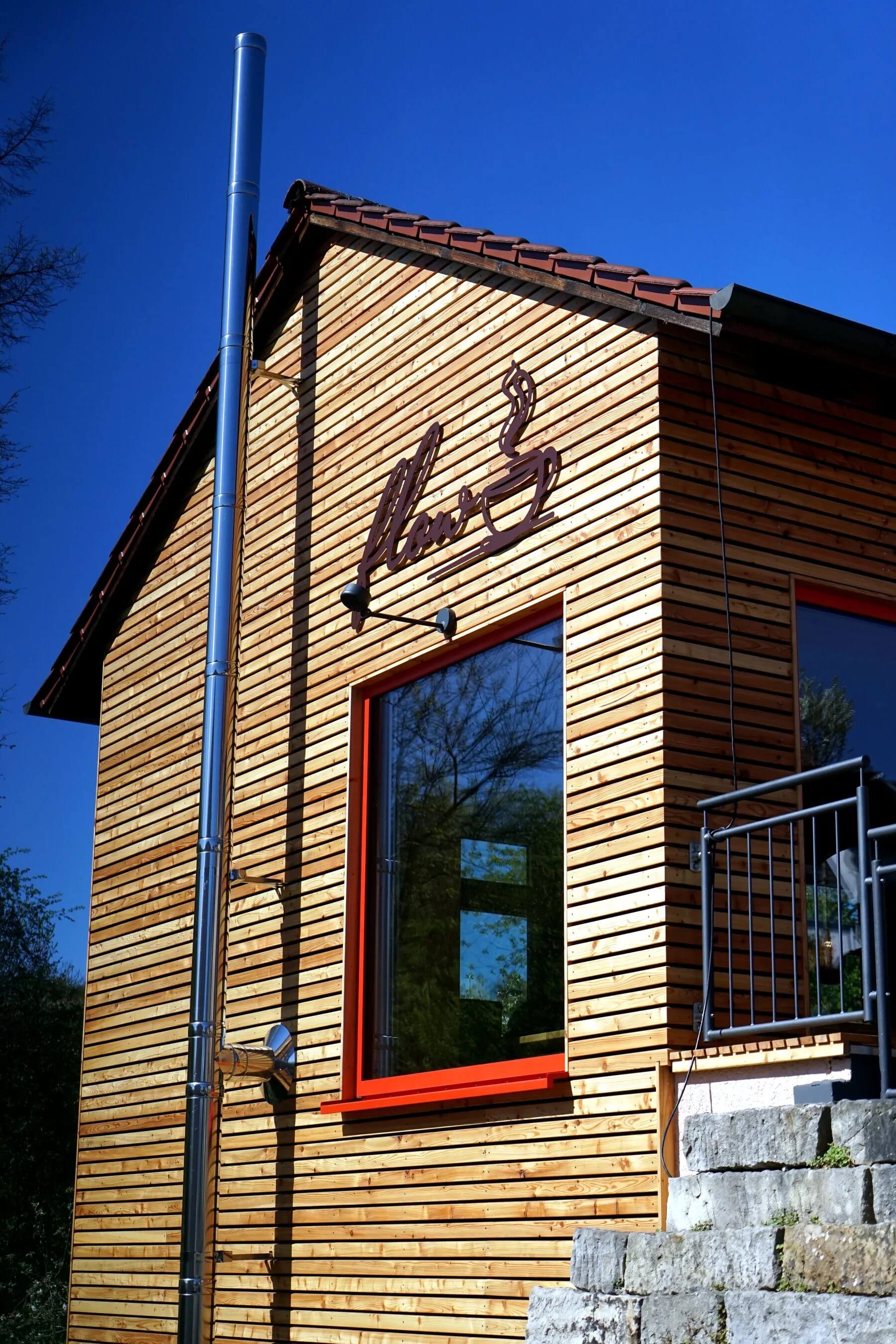 Außenansicht des Dorfladen Cafés Marktgraitz mit Holzfassade und rotem Fensterrahmen