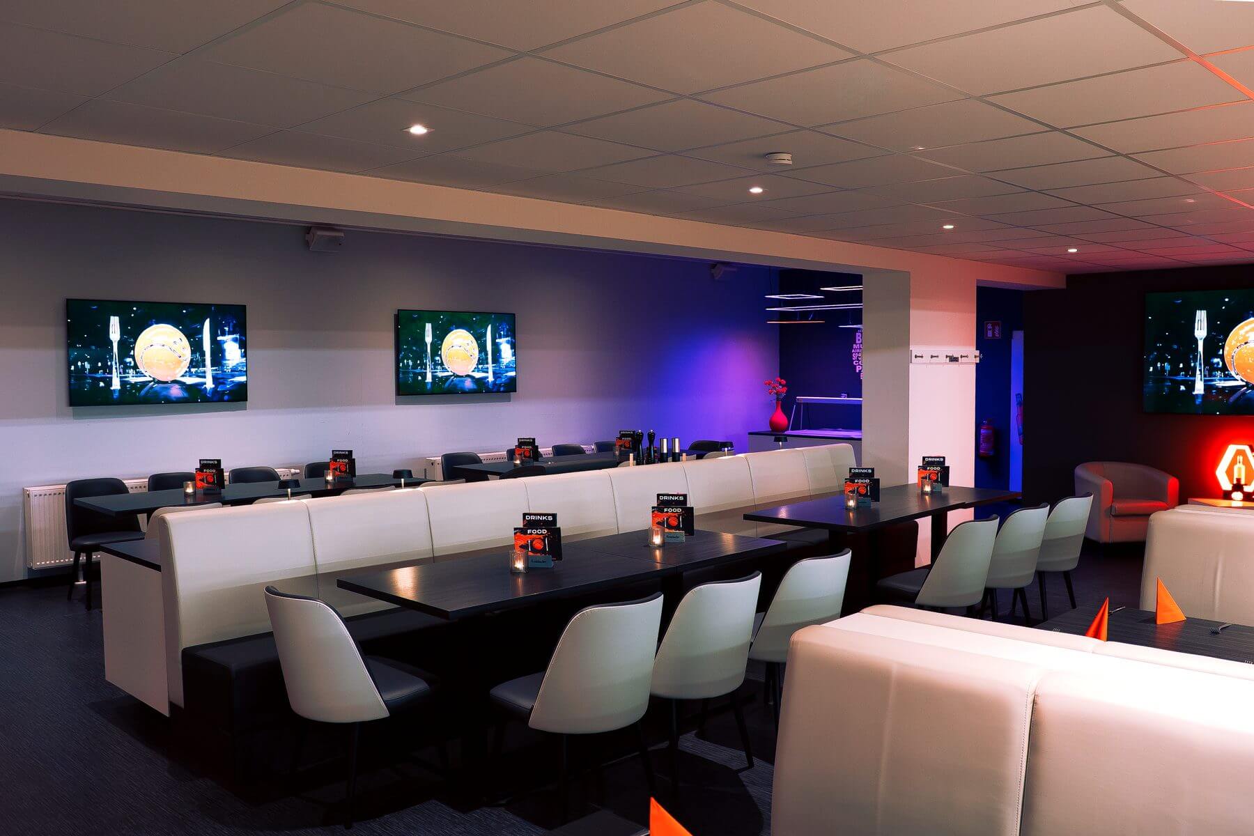 Loungebereich der Players Lounge Finnentrop mit Tischreihen, Sitzmöbeln und TV-Wand